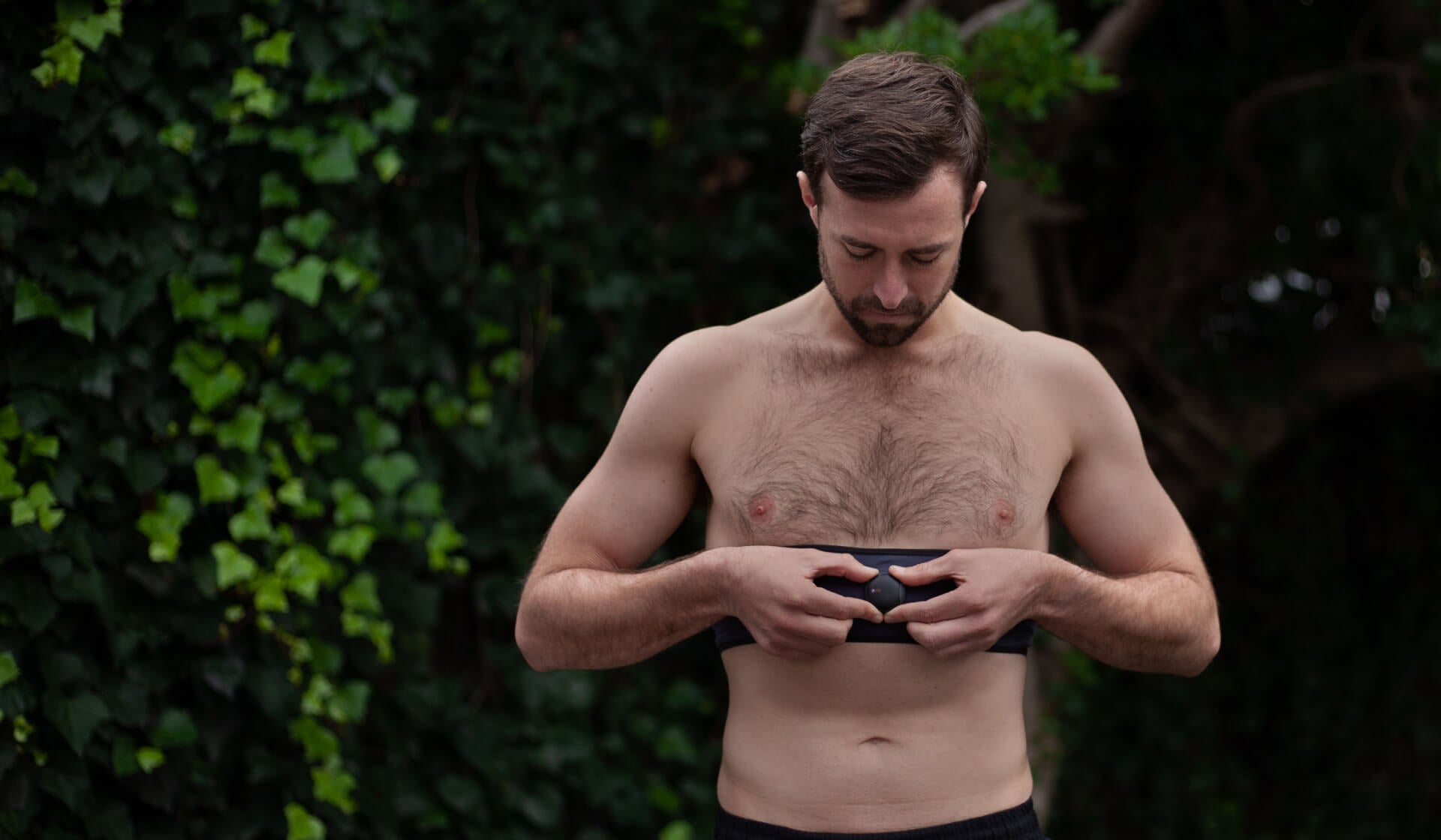 Man outdoors, attaching the Oxa breathing coach device to his waistband preparing for a focused breathing session to enhance his wellbeing and resilience.